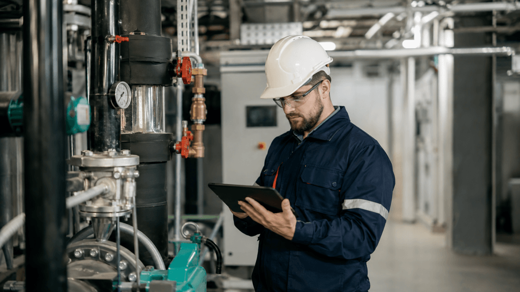 Audytor energetyczny analizujący instalację techniczną w zakładzie przemysłowym podczas pracy nad zarządzaniem energią.
